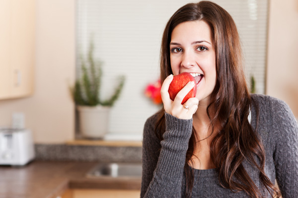 Frau isst Apfel zu Hause