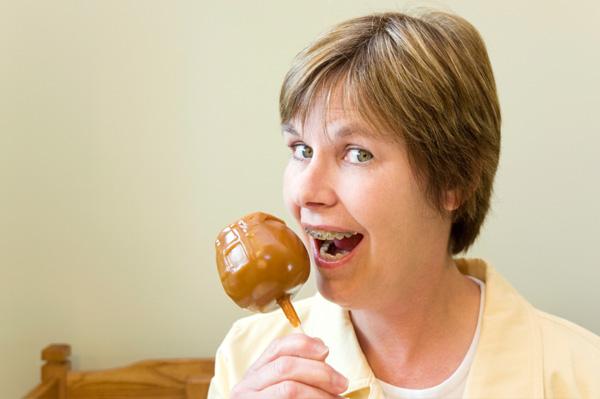 Frau mit Zahnspange, die Süßigkeitsapfel isst