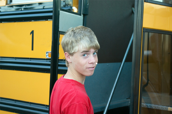 Nervózní dospívající chlapec nastupující do autobusu