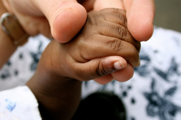 Mujer sosteniendo la mano de bebés africanos