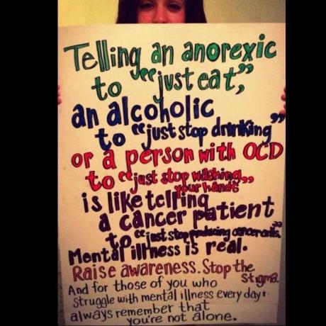 Mujer sosteniendo un cartel sobre el estigma de la salud mental.