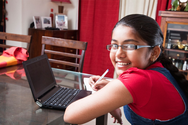 Tween-Mädchen macht Hausaufgaben im Wohnzimmer auf Laptop