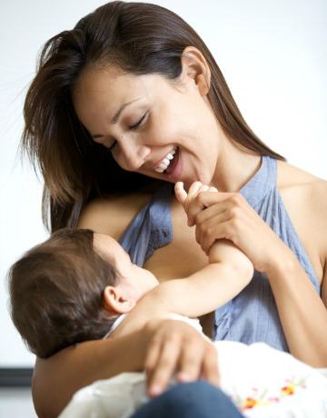 Laimīga mamma, kas baro bērnu ar krūti