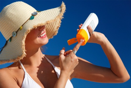 Жінка, застосовуючи сонцезахисний крем на пляжі