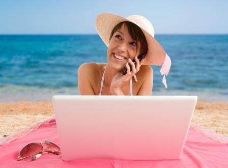 Mamá en el teléfono y la computadora en la playa.