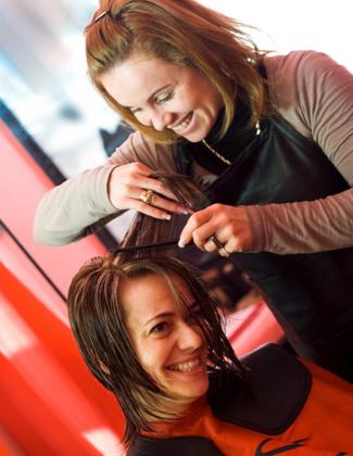 Kampaaja leikkaa naisen hiuksia