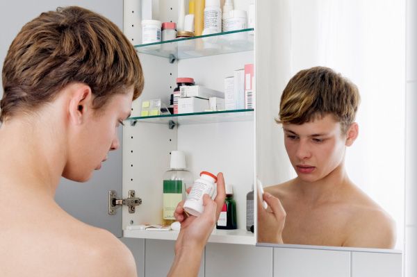 tinédzser fiú keresi a gyógyszeres szekrényt