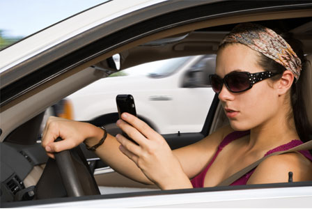 giovane donna che guida e manda sms