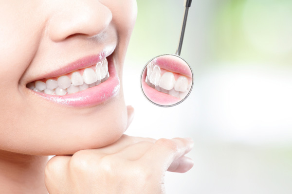 Kobieta uśmiechająca się w lustrze dentysty