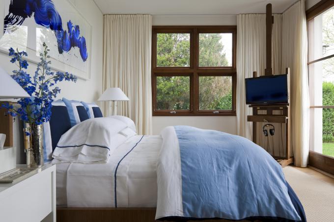 Weißes Zimmer mit blauen Kissen und blauen Kunstwerken