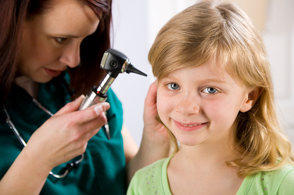Orvos fiatal lányok fülét vizsgálja