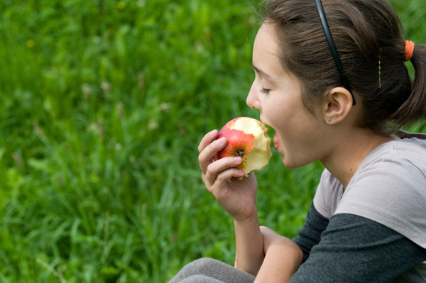 Adolescente comiendo manzana