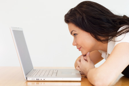 Ragazza che fissa amorevolmente il laptop sul letto