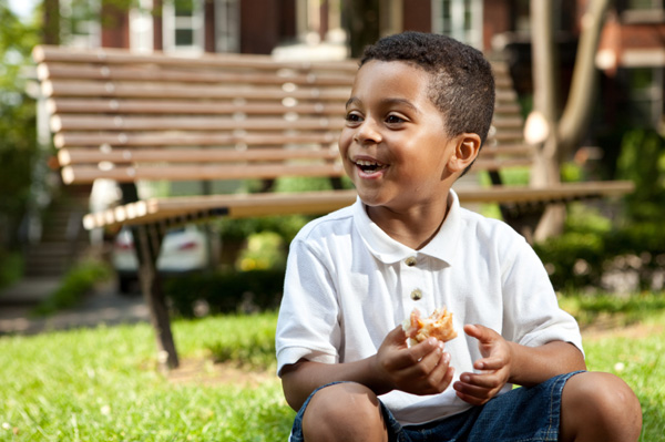 Маленький хлопчик їсть бутерброд на ходу