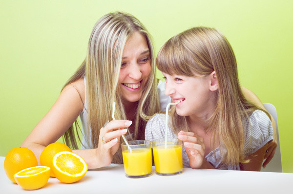 Mutter und Tochter trinken Orangensaft
