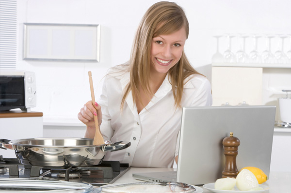 Nő főzés laptop közelében