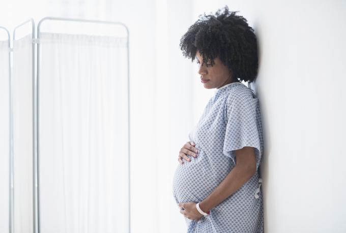 Schwangere afroamerikanische Mutter hält Bauch im Krankenhaus