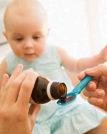 mama geeft hoestsiroop aan baby