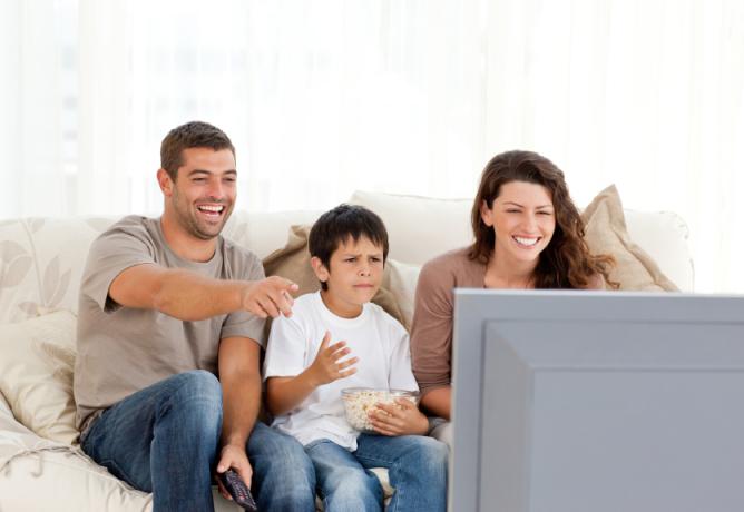 Rodzina śmiejąca się podczas wspólnego oglądania telewizji