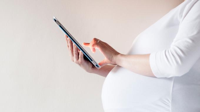 Kobieta w ciąży z komputerem typu tablet