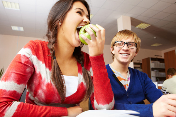 Chica universitaria comiendo manzana
