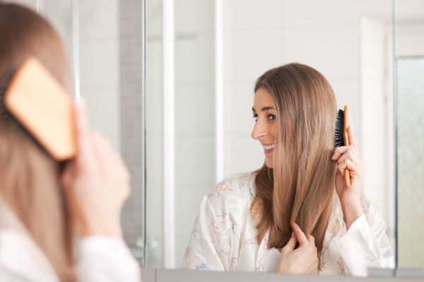 Frau bürstet ihr Haar im Spiegel