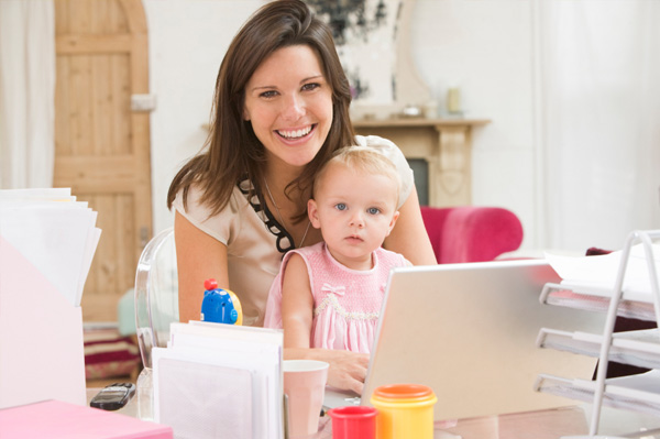 Mama arbeitet mit Kleinkind am Laptop