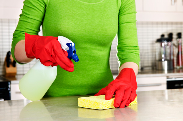 Nő takarítja a konyhát zöld tisztítószerrel