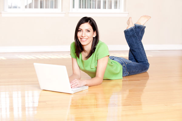 Kobieta korzysta z laptopa na drewnianej podłodze