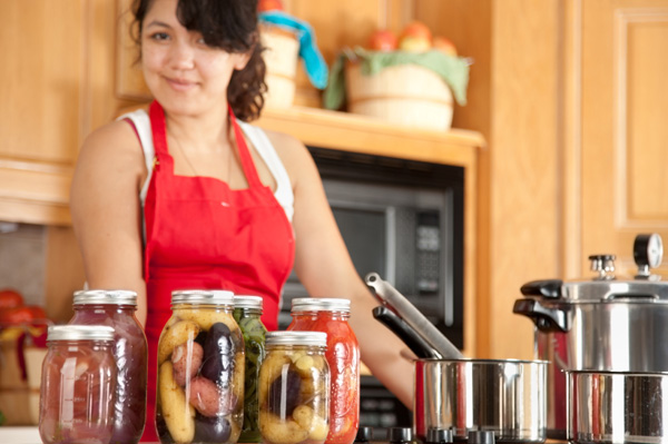 Жінка консервує овочі в домашніх умовах