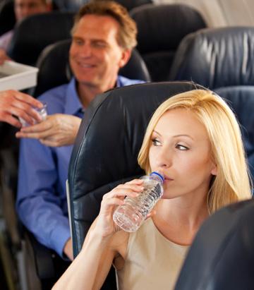 Nainen juo vettä lentokoneessa