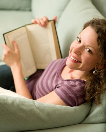 Frau liest Buch auf der Couch