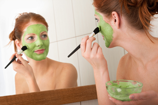 Frau, die grüne Gesichtsmaske aufsetzt