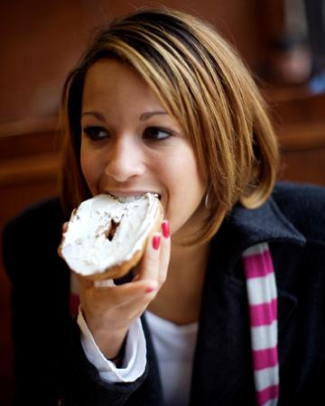 Sieviete kafejnīcā ēd bageli