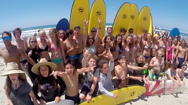 Para pekemah dari Endless Summer Surf Camp berpose di depan papan selancar mereka di pantai.