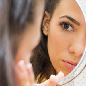 Sieviete skatās uz ādu spogulī