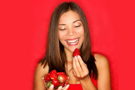 Sieviete sarkanā krāsā ēd zemenes