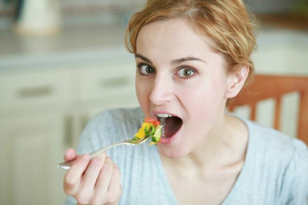 Жінка їсть овочі