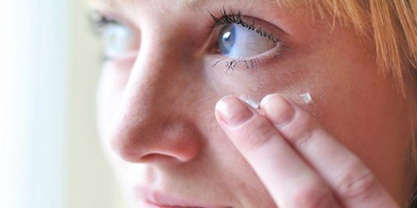 Vrouw in de 30 die oogcrème aanbrengt