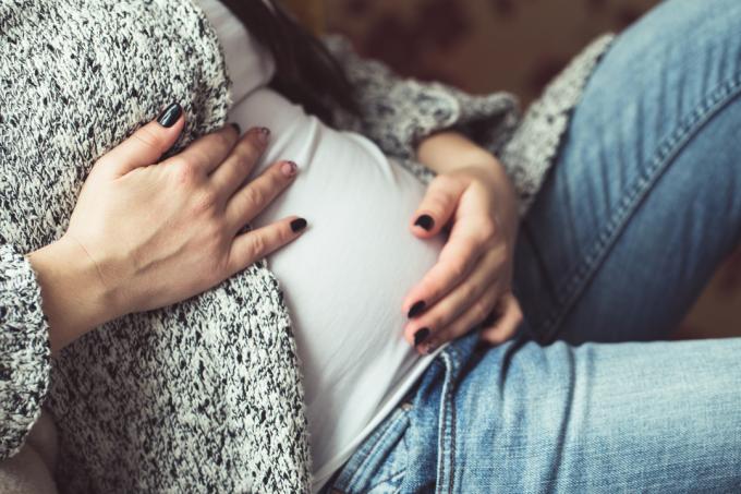 Mujer embarazada joven sentada en el sofá de cerca